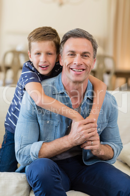 Smiling son embracing a father in living room Smiling son embracing a father in living room