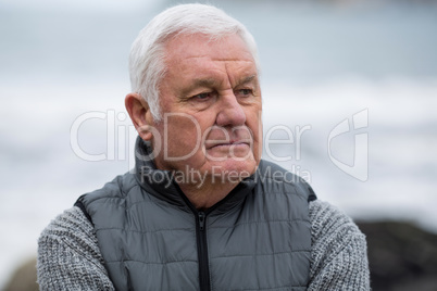 Thoughtful senior man standing near beach