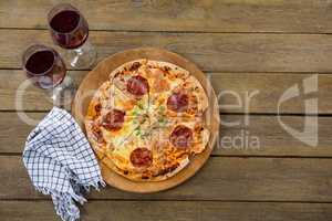 Italian pizza served in a pizza tray with red wine