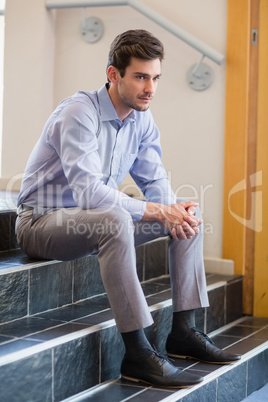 Thoughtful businessman sitting on steps