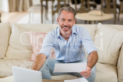 Happy man holding a bill in living room