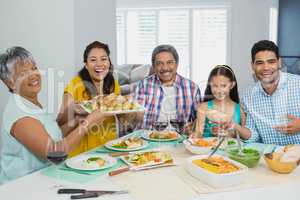 Happy multi generation family having meal on table at home