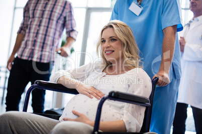 Male doctor pushing a pregnant woman in wheel chair