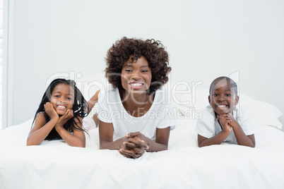 Portrait of mother and kids lying on bed