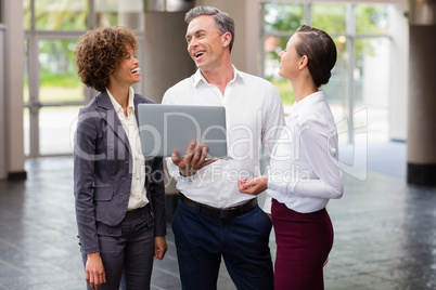 Business executives holding laptop and laughing