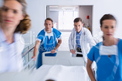 Doctors pushing emergency stretcher bed in corridor