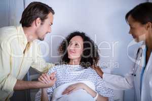 Doctor and man comforting pregnant woman in ward