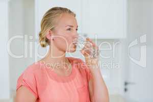 Woman drinking water from glass in kitchen