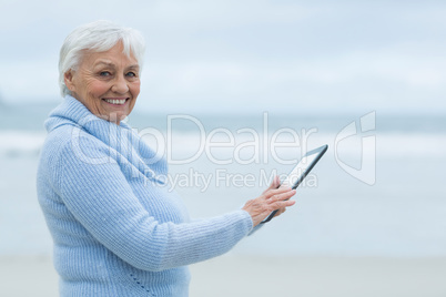 Senior woman using digital table on the beach