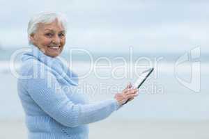 Senior woman using digital table on the beach