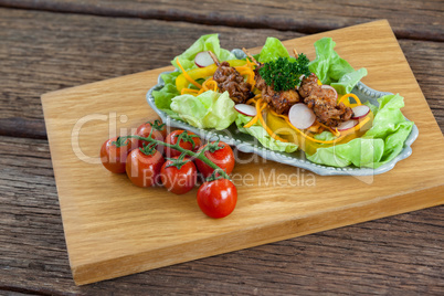 Vegetable salad and cherry tomatoes on wooden board