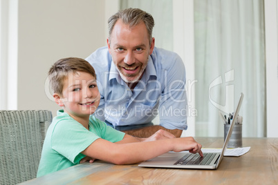 Father and son using laptop at desk