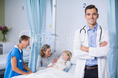 Portrait of smiling doctor standing with arms crossed