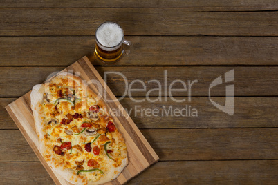 Delicious pizza served on pizza tray with a glass of beer on wooden plank