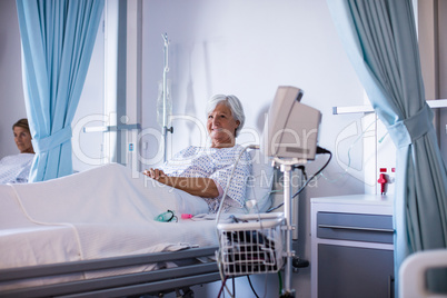 Female senior patient smiling and relaxing on a bed in the ward
