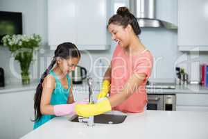 Mother assisting her daughter in cleaning vessel