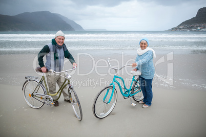 Senior couple standing with bicycles on the beach