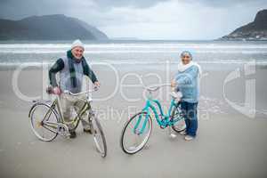 Senior couple standing with bicycles on the beach