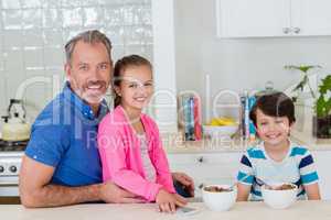 Smiling father and kids having breakfast in kitchen