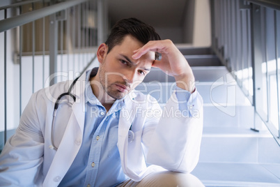 Portrait of thoughtful doctor sitting on staircase