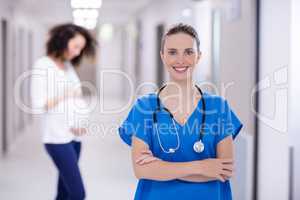 Portrait of female doctor standing with arms crossed in corridor