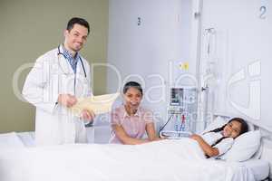 Portrait of doctor and girl patient in hospital bed