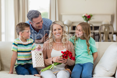 Portrait of parents and kids sitting on sofa with present in living room