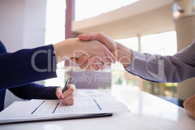 Businesswoman shaking hands with colleague at desk