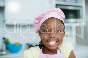 Smiling girl in chefs hat at home