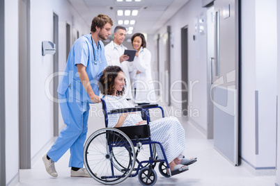 Doctor pushing a pregnant woman on wheelchair