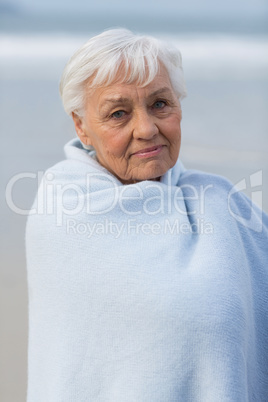 Senior woman wrapped in shawl at beach