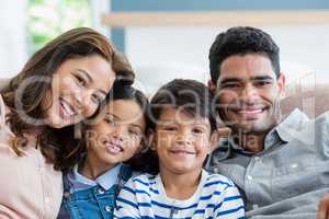 Portrait of happy parents and kids sitting on sofa in living room