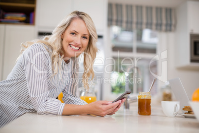 Beautiful woman using mobile phone in kitchen