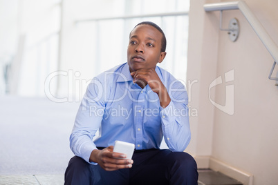 Thoughtful businessman holding mobile phone