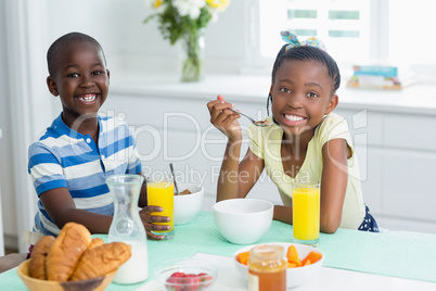 Siblings having breakfast on dining table at home