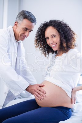 Doctor touching pregnant womans belly in ward