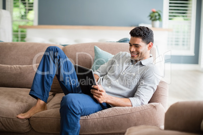 Man sitting on sofa and using digital tablet in living room