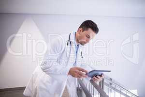 Doctor using digital tablet in corridor