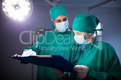Male and female surgeon discussing over a medical report of the patient