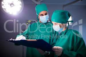 Male and female surgeon discussing over a medical report of the patient