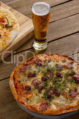 Delicious pizza served on wooden board with a glass of beer