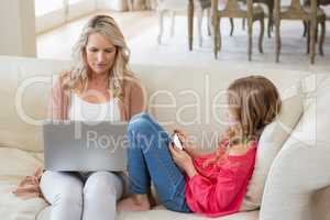 Mother and daughter using laptop and mobile phone