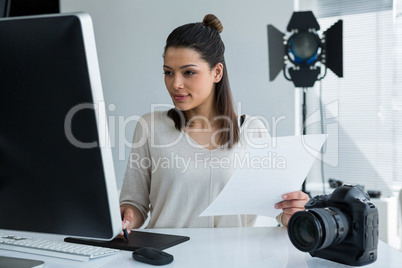 Female photographer using graphic tablet at desk