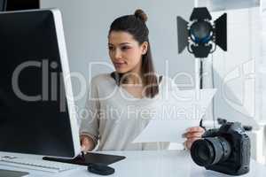 Female photographer using graphic tablet at desk