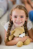 Girl holding a teddy bear on bed in bedroom