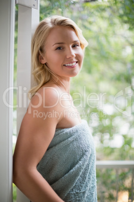 Smiling woman in towel standing at balcony