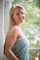 Smiling woman in towel standing at balcony