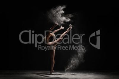 Graceful girl dancing in cloud of dust studio shot