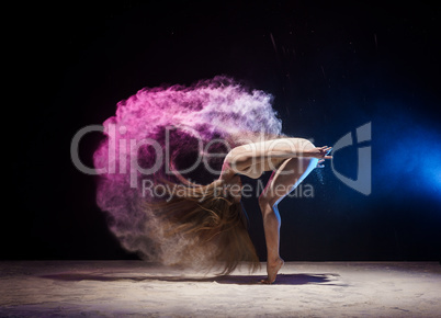 Graceful female gymnast in cloud of color dust
