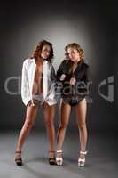 Blonde and brunette in unbuttoned shirts in studio